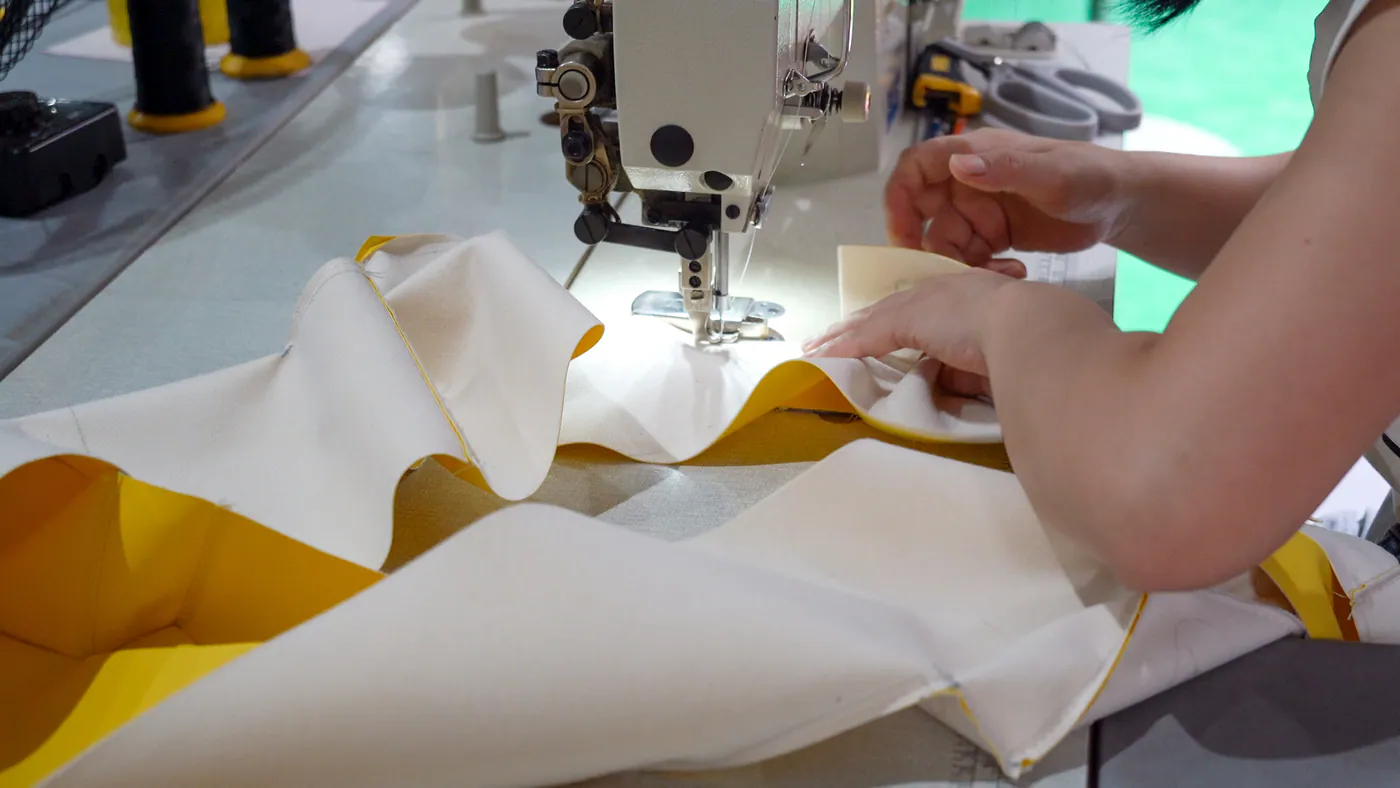 Hands sewing a colorful protective cover in the workshop