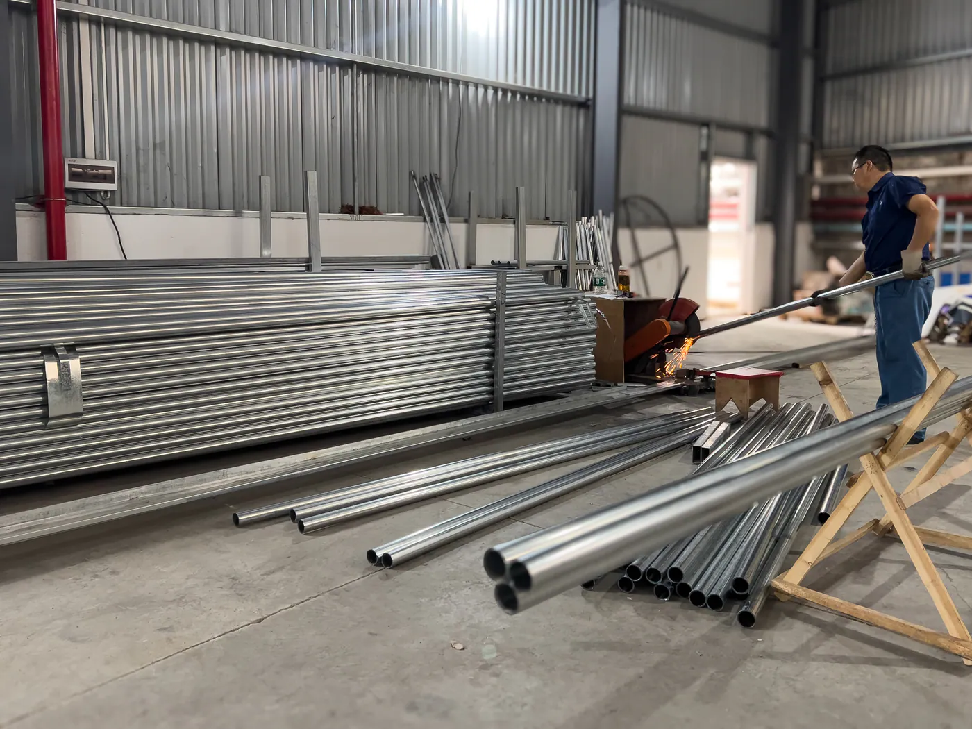 Worker cutting metal tubes in the production workshop