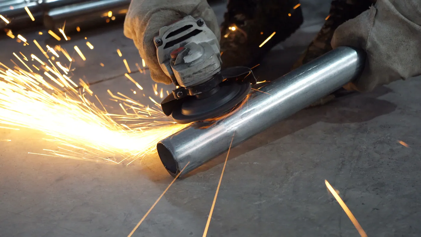 Close view of a playground metal tube being ground in the workshop